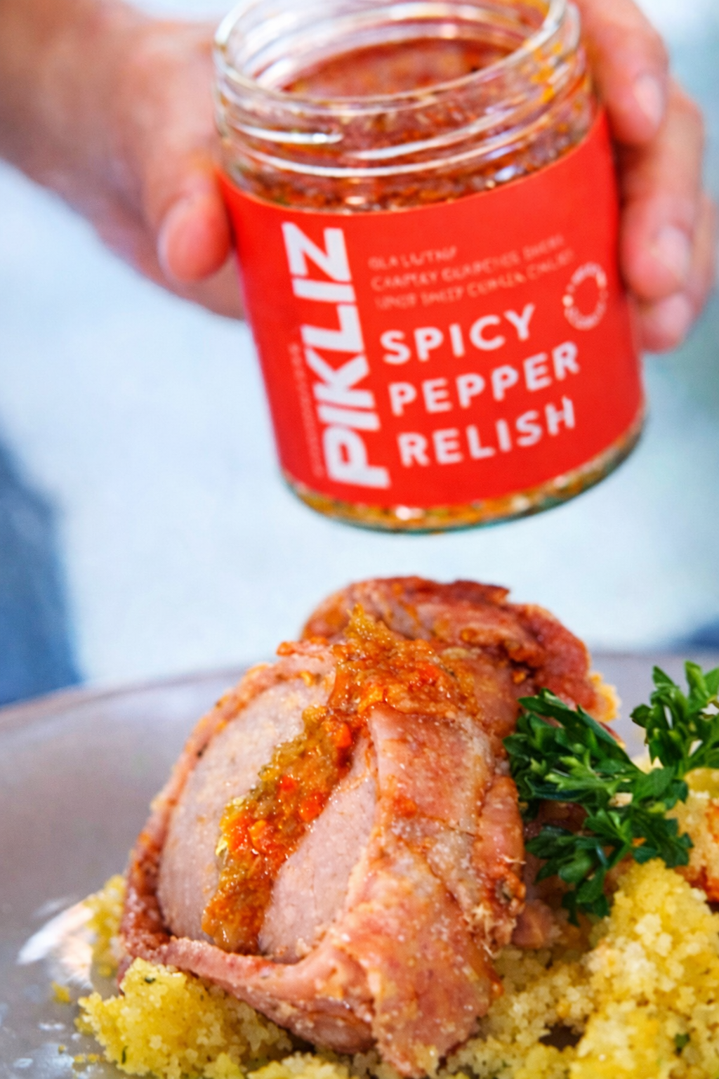 Bacon-wrapped pork loin topped with Alexandra’s Pikliz® Spicy Pepper Relish, served over pineapple panko crumbs