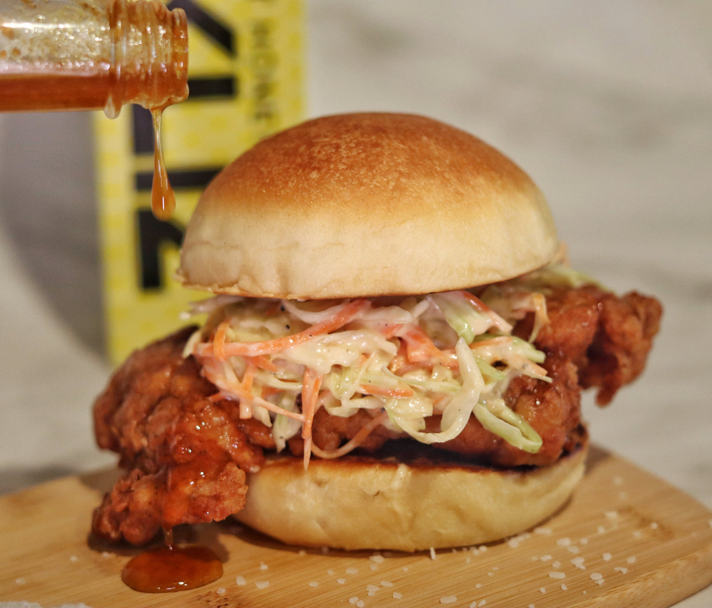 Nashville-style hot honey chicken sandwich with coleslaw on a brioche bun drizzled with Alexandra’s Pikliz® Hot Honey Sauce